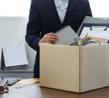 Person seen from neck down packing up belongings into cardboard box in office