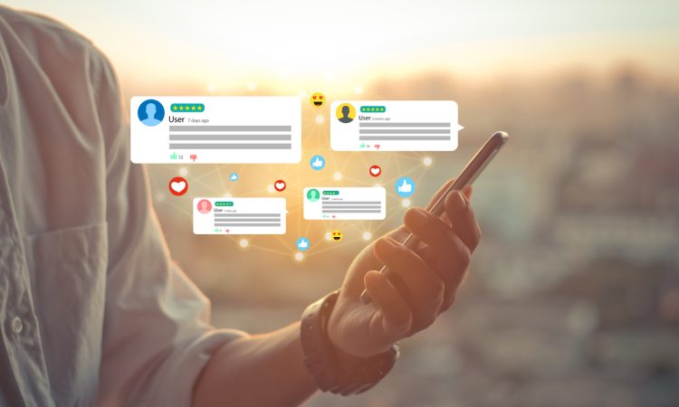 Hand holding phone with social media icons hovering above it