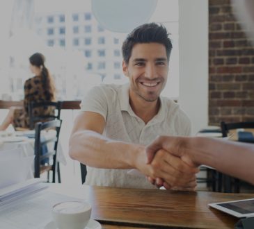 Two people shaking hands in cafe