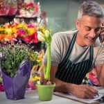 Male florist taking order on mobile phone at his flower shop