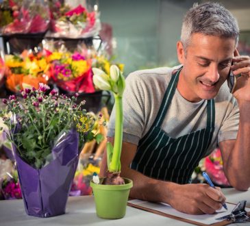 Male florist taking order on mobile phone at his flower shop