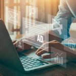 Person typing on computer overlaid with icons representing digital marketing (chart, megaphone, ad)