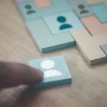 Hand building puzzle from wooden tiles with people icons on them