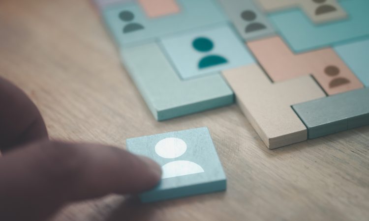 Hand building puzzle from wooden tiles with people icons on them