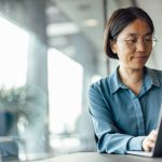 East Asian woman working on laptop in office