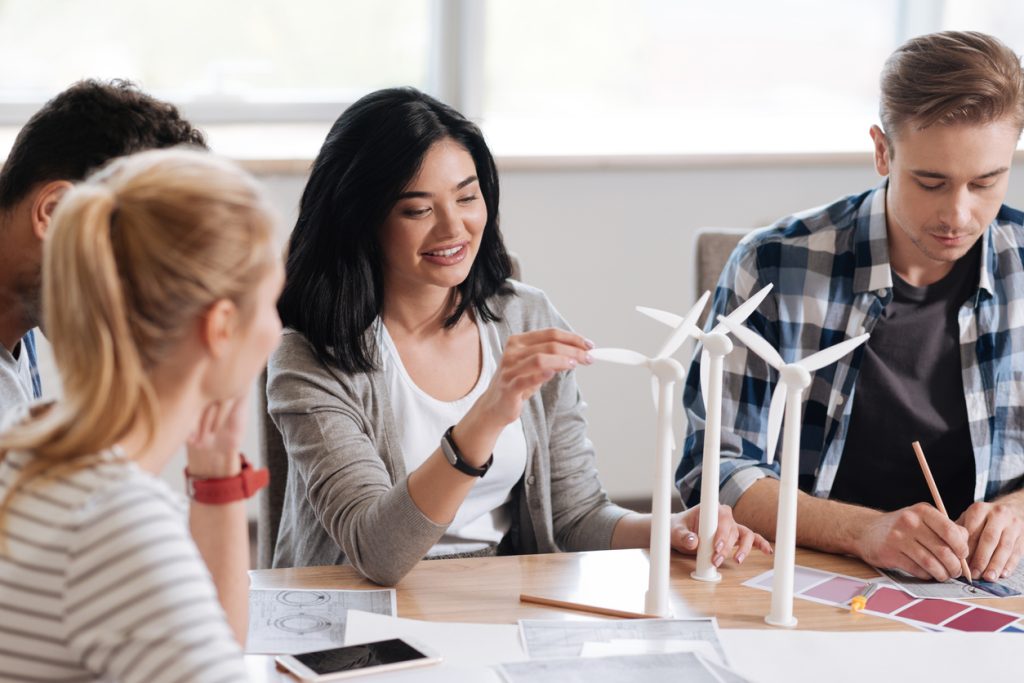 Group of young people sitting at table with models of wind turbines
