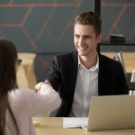 Man and woman shaking hands while sitting across table from one another