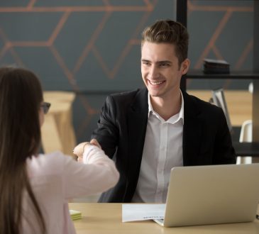 Man and woman shaking hands while sitting across table from one another