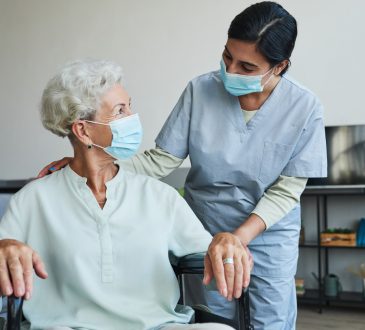 Portrait of female nurse assisting senior woman in wheelchair a