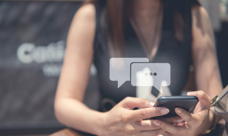 Woman texting with chat bubbles above phone