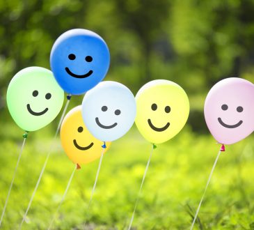 Smiley face balloons hovering over grass