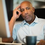 Man sitting at desk looking unhappy