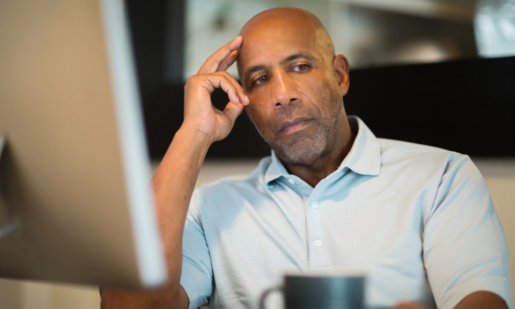 Man sitting at desk looking unhappy