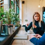 Two people talking in coffee shop near window