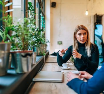 Two people talking in coffee shop near window