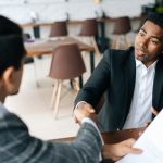 Two men shaking hands across desk