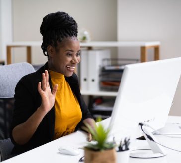 Woman waves at computer during video call
