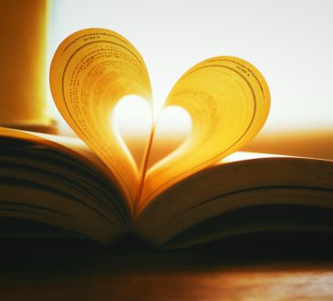 Book silhouetted by sun with middle pages folded into shape of a heart
