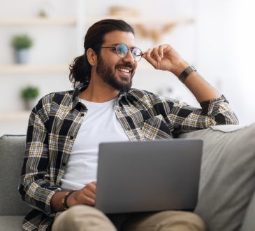 Man sitting on couch working on laptop