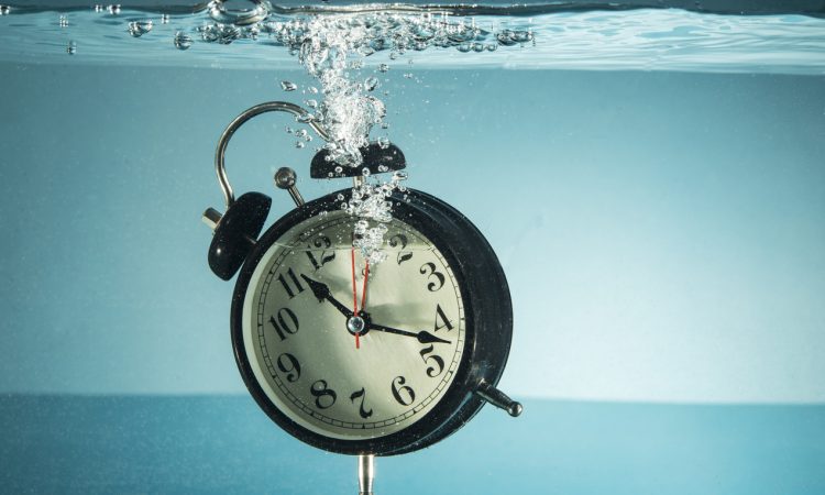 Black clock with white face sinking in water
