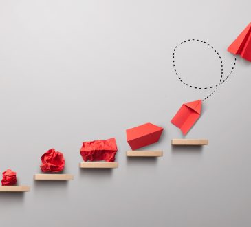 Wooden steps with different stages of making a paper airplane, creating something from nothing