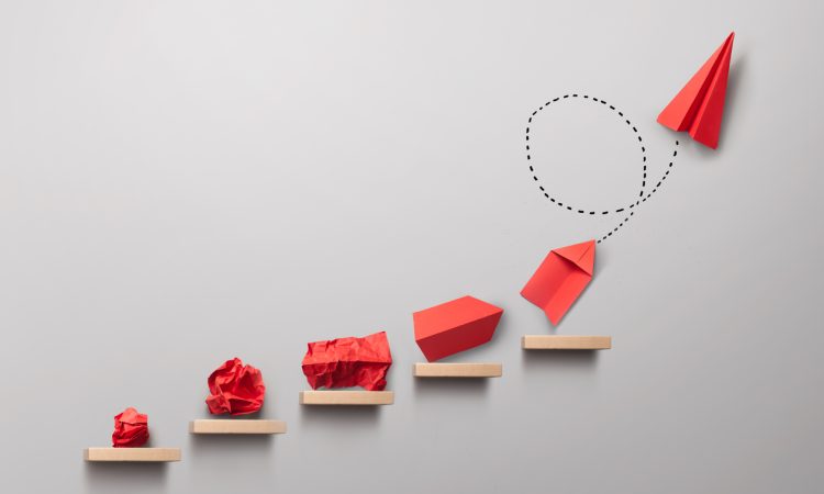 Wooden steps with different stages of making a paper airplane, creating something from nothing