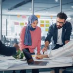Multi-racial group of co-workers standing around table during meeting