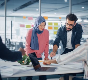 Multi-racial group of co-workers standing around table during meeting
