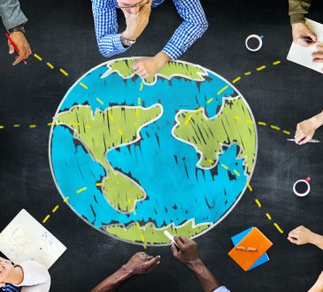 Photo illustration - bird's eye view of people sitting around globe drawn on table
