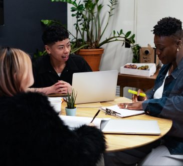 A group of co-workers of various genders having a meeting at a round table in an office.