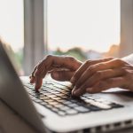 Close-up of man's hands typing on keyboard.