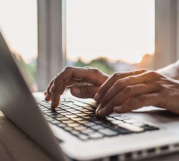 Close-up of man's hands typing on keyboard.