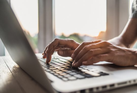 Close-up of man's hands typing on keyboard.