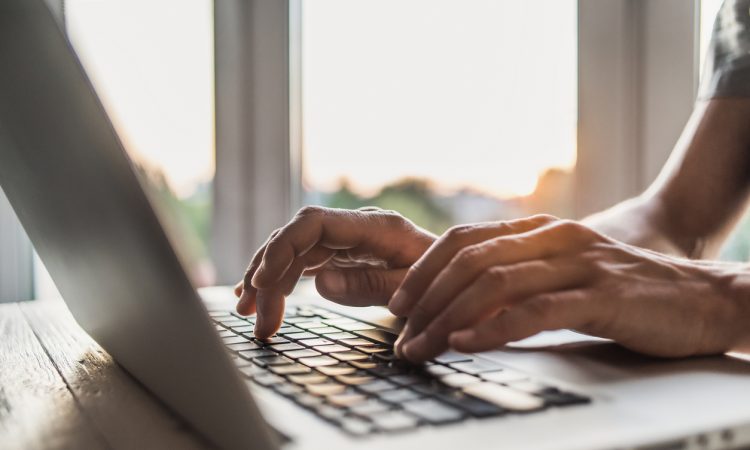 Close-up of man's hands typing on keyboard.