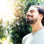 Man standing outside meditating with eyes closed