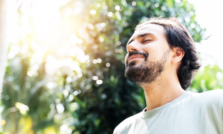 Man standing outside meditating with eyes closed