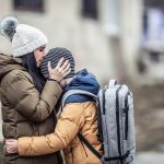 Woman wearing winter jacket hugging son outside