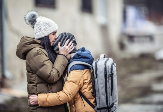 Woman wearing winter jacket hugging son outside