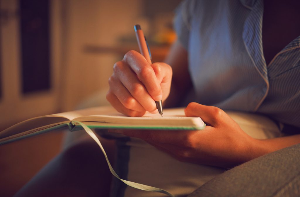 Close-up of person's hands writing in journal