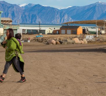 Inuit woman walking with baby in Pond Inlet, Baffin Island.