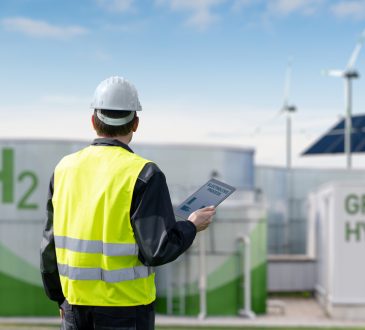 Engineer with tablet computer on a background of Green Hydrogen factory