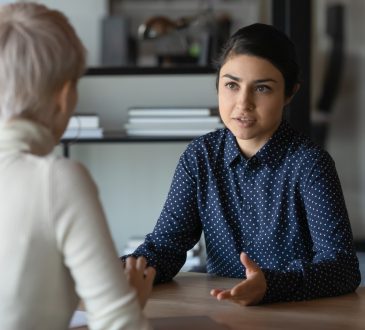 Two people sitting at table talking at work
