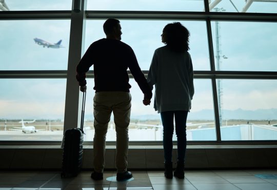 Silhouetted couple holding hands at airport