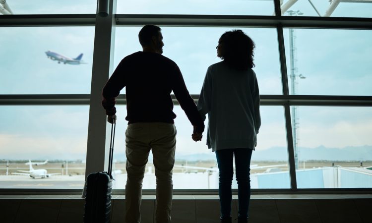 Silhouetted couple holding hands at airport