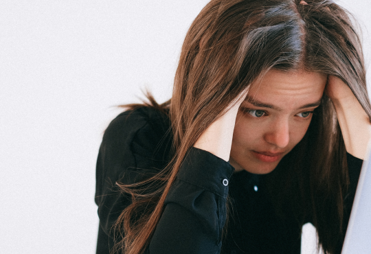Woman looking at laptop and feeling stressed.
