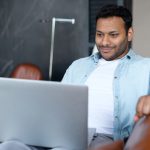 Man looking at laptop slightly smiling