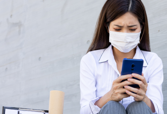 Woman sitting down using phone after getting fired due to pandemic layoffs