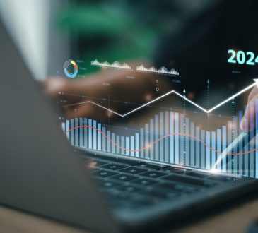 Hands typing on laptop with overlay of charts and "2024"