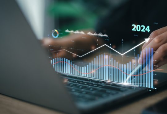 Hands typing on laptop with overlay of charts and "2024"