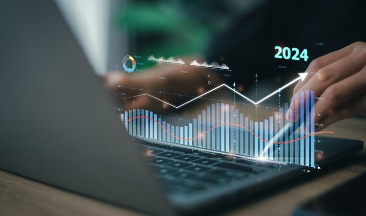 Hands typing on laptop with overlay of charts and "2024"